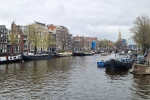 V dáli věž Montelbaanstoren u grachtu v Amsterdamu